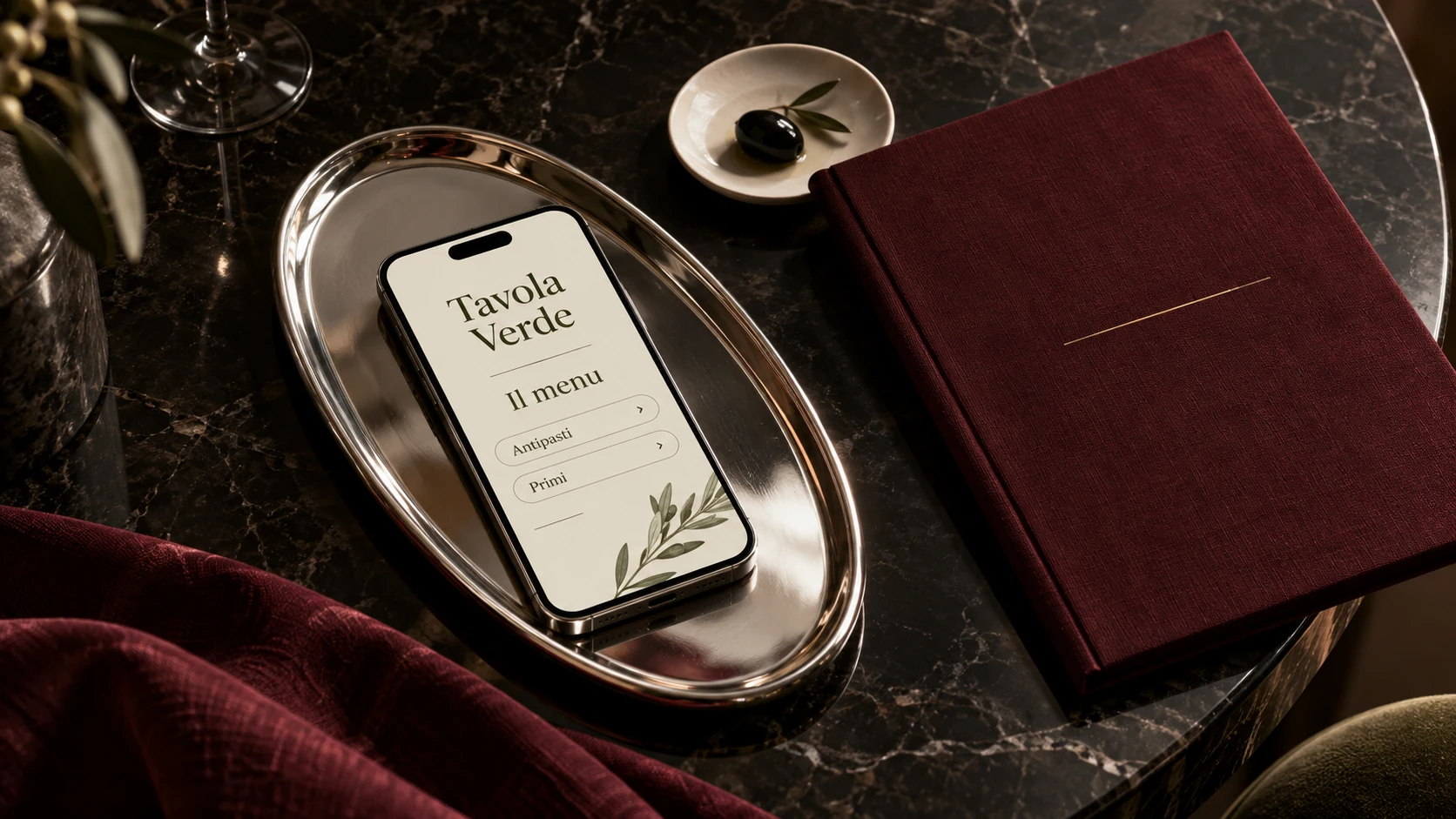 Menu digitale su smartphone in un vassoio argentato, con una cartella bordeaux e un piattino avorio